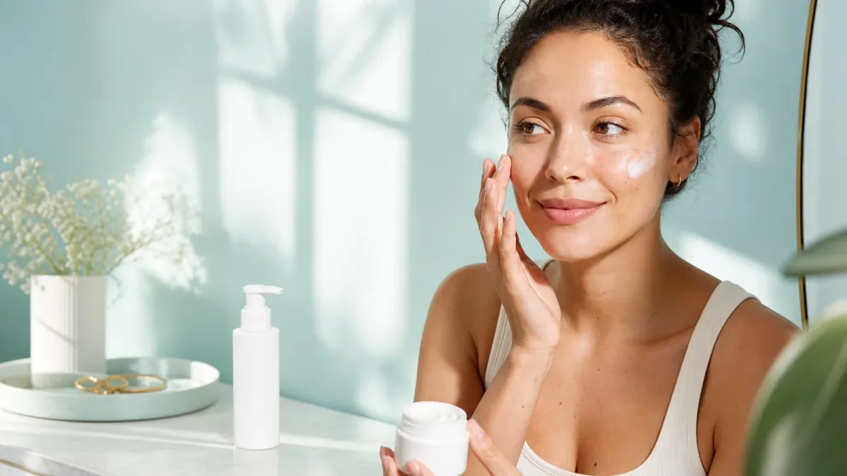 Woman applying a facial moisturizer with SPF during a bright morning skincare routine