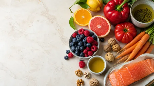 Antioxidant-rich berries, citrus, vegetables, green tea, nuts, olive oil and salmon arranged on pale stone