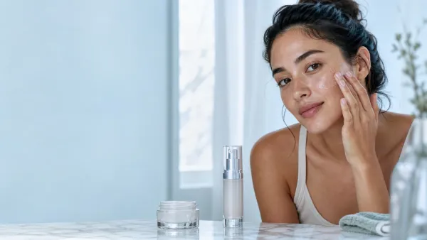 Woman applying a translucent gel moisturizer at a bright skincare vanity