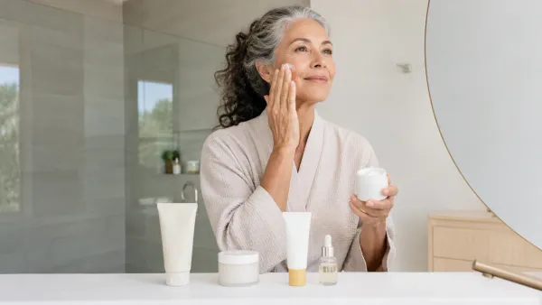 Woman with natural mature skin applying moisturizer beside a simple aging-skin routine