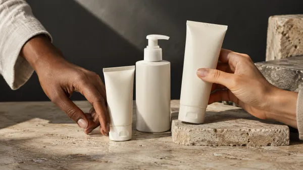 Two adult hands with different skin tones arranging generic, unbranded skincare containers